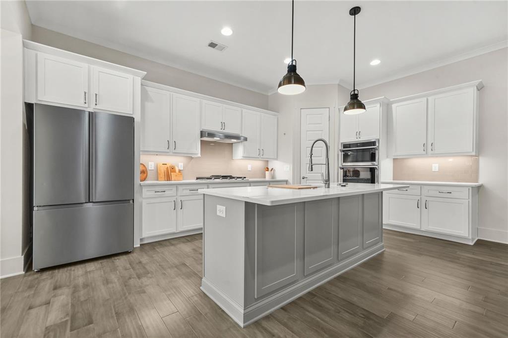 265 Holland Road Powder Springs, GA 30127 - Photo 3 of 27 a kitchen with kitchen island white cabinets and white appliances