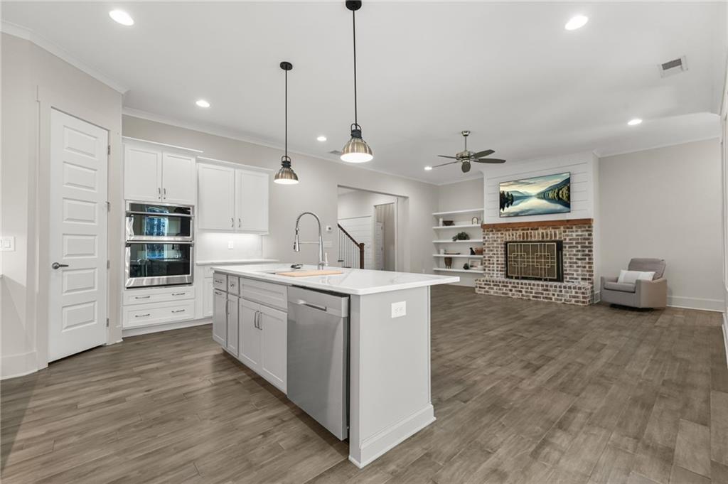 265 Holland Road Powder Springs, GA 30127 - Photo 6 of 27 a kitchen with kitchen island a stove a sink a refrigerator and a fireplace with wooden floor