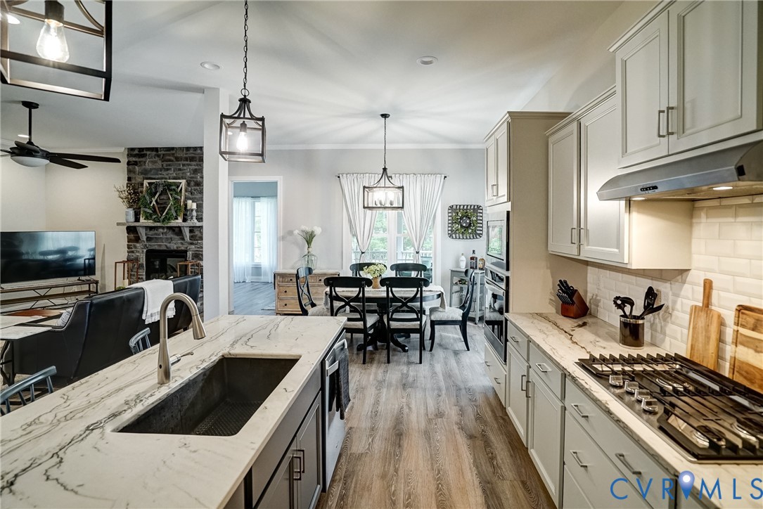 4669 Woburn Road Providence Forge, VA 23140 - Photo 14 of 78 a kitchen with stainless steel appliances a stove a sink a kitchen island a dining table and chairs with wooden floor