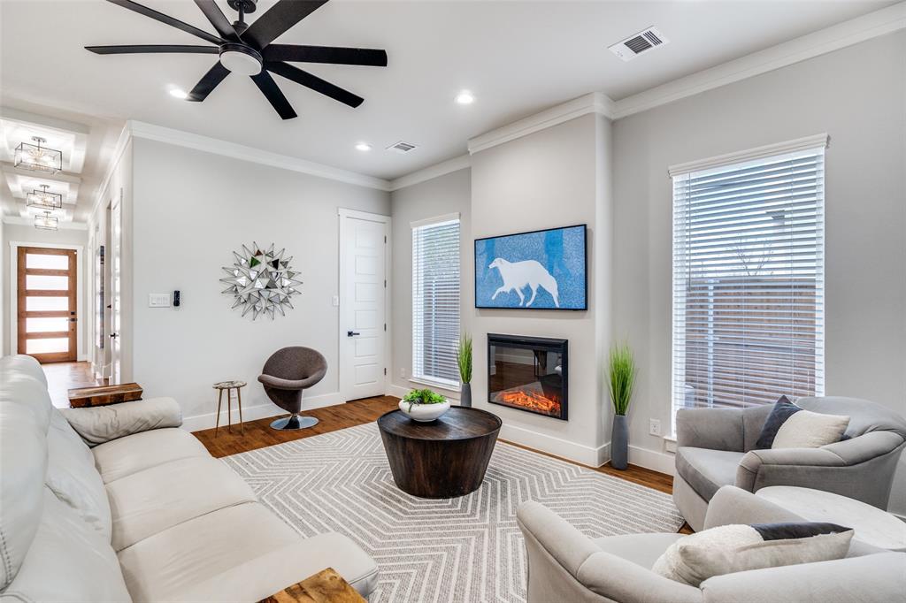 518 Crete Street Dallas, TX 75203 - Photo 4 of 27 Living area with ornamental molding, a glass covered fireplace, ceiling fan, wood finished floors, and plenty of natural light