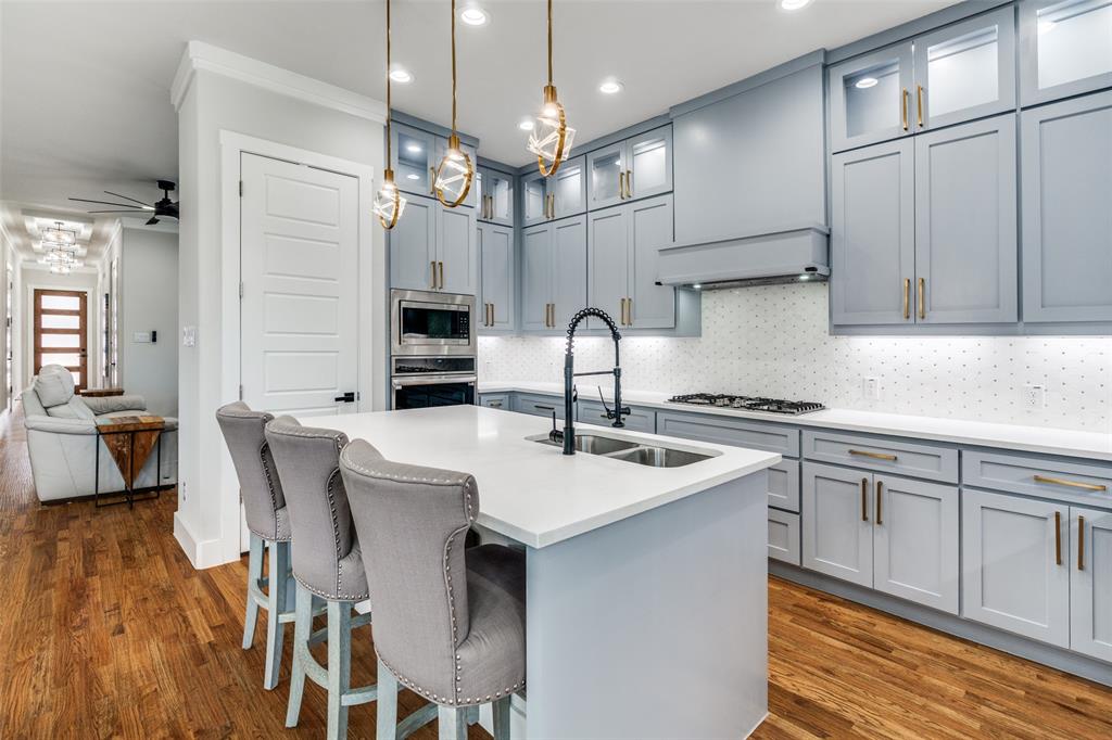 518 Crete Street Dallas, TX 75203 - Photo 6 of 27 Kitchen with glass insert cabinets, a kitchen bar, tasteful backsplash, a center island with sink, and pendant lighting