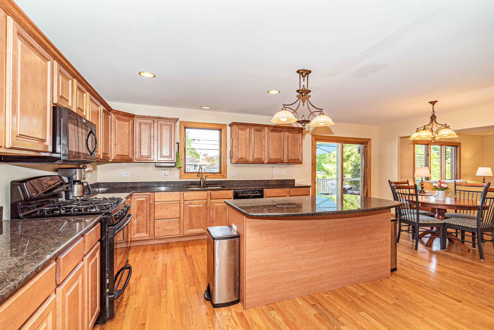 10551 Princess Avenue Chicago Ridge, IL 60415 - Photo 5 of 26 a kitchen with stainless steel appliances granite countertop a stove top oven a kitchen island a dining table and chairs with wooden floor