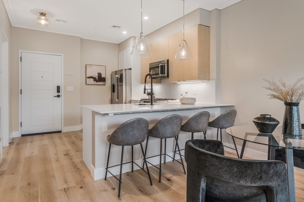 70 Leo M Birmingham Parkway, Unit U307 Boston, MA 02135 - Photo 1 of 35 a kitchen with kitchen island a dining table chairs cabinets and sink