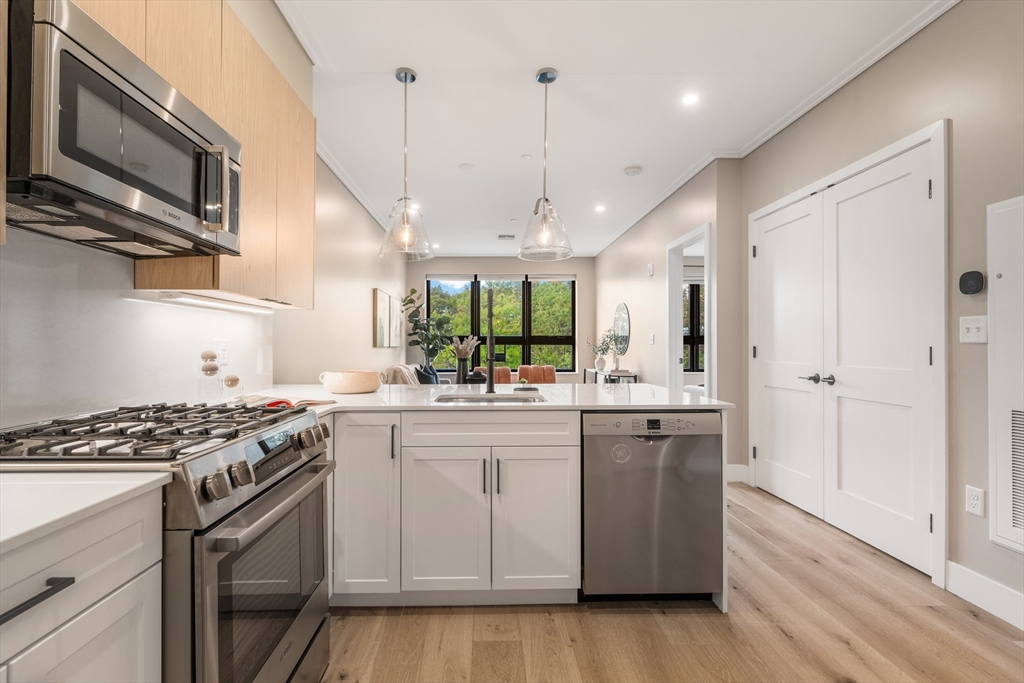 70 Leo M Birmingham Parkway, Unit U307 Boston, MA 02135 - Photo 8 of 35 a kitchen with stainless steel appliances granite countertop a stove and a sink