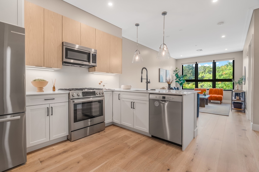 70 Leo M Birmingham Parkway, Unit U307 Boston, MA 02135 - Photo 9 of 35 a kitchen with stainless steel appliances granite countertop a stove a sink dishwasher a refrigerator and a microwave oven with wooden floor
