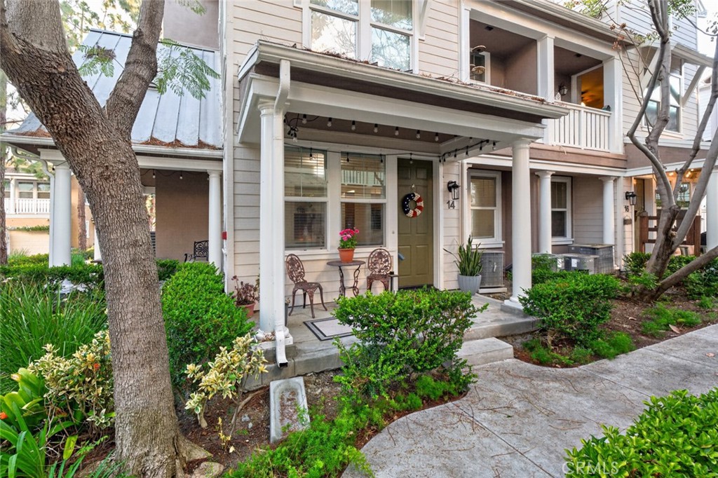 a view of a house with potted plants and a large tree
