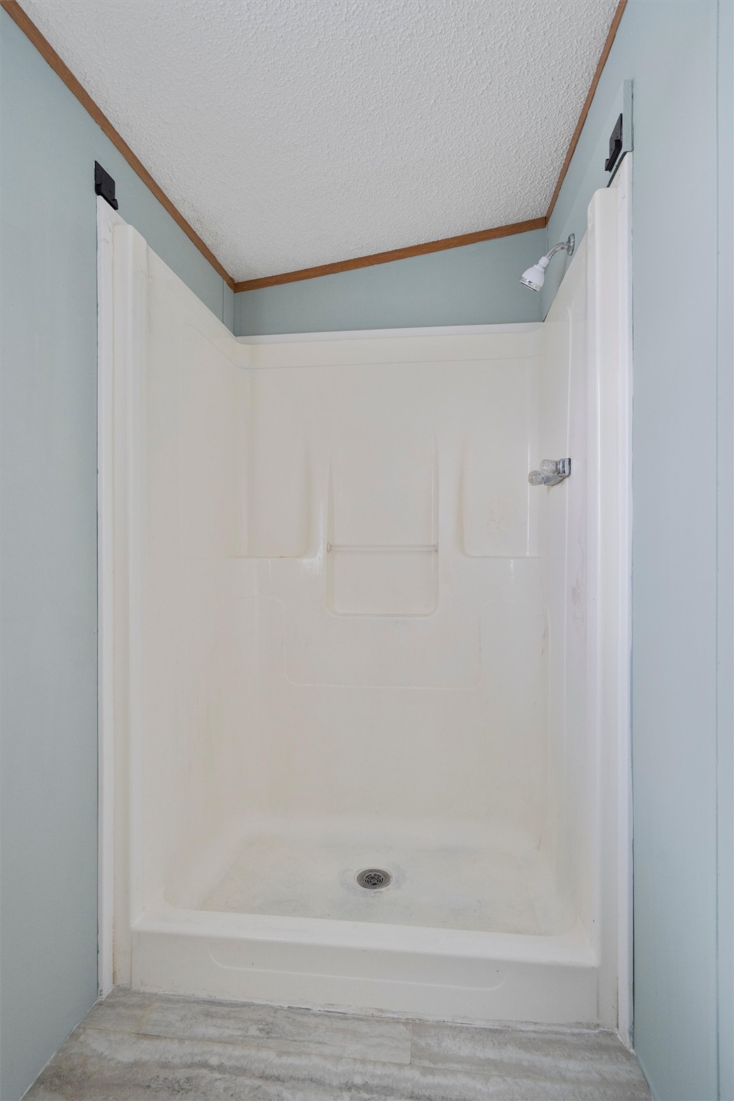 3075 Old Black Colony Road, Unit D Buda, TX 78610 - Photo 15 of 26 A functional walk-in shower insert is flanked by soft blue walls and neutral flooring.