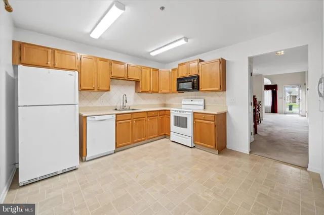a kitchen with a refrigerator a stove top oven a sink and cabinets