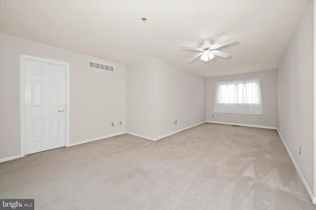 an empty room with a window and ceiling fan