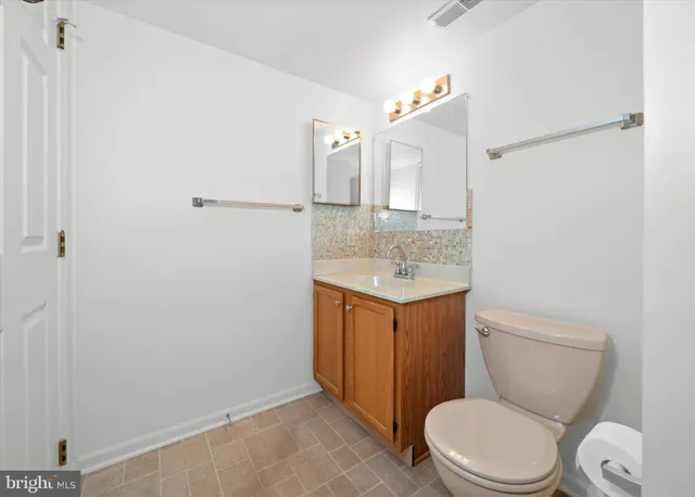 a bathroom with a toilet sink vanity granite and shower
