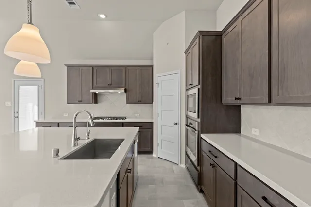 a kitchen with stainless steel appliances granite countertop a refrigerator a sink a stove and a refrigerator