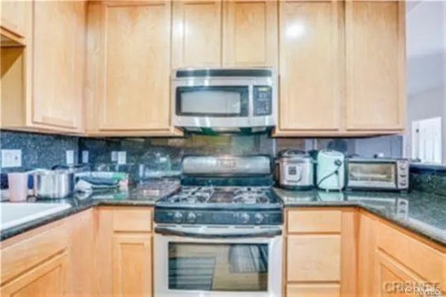 a kitchen with stainless steel appliances granite countertop a stove a sink and a white cabinets
