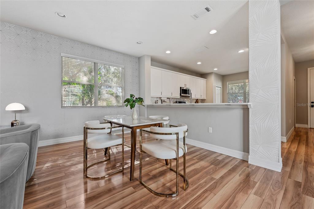 7935 Winter Wren Street Winter Garden, FL 34787 - Photo 11 of 36 a kitchen with a dining table chairs and white cabinets next to a window