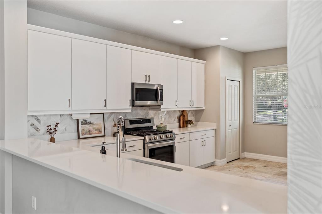 7935 Winter Wren Street Winter Garden, FL 34787 - Photo 12 of 36 a kitchen with white cabinets and appliances