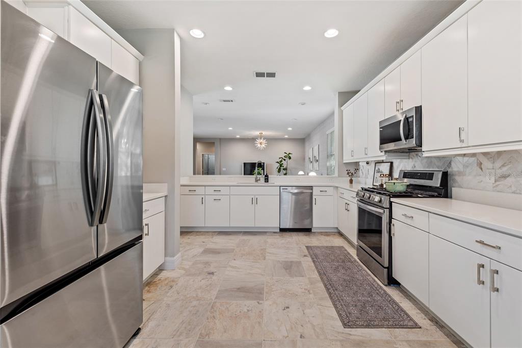 7935 Winter Wren Street Winter Garden, FL 34787 - Photo 15 of 36 a kitchen with white cabinets and stainless steel appliances