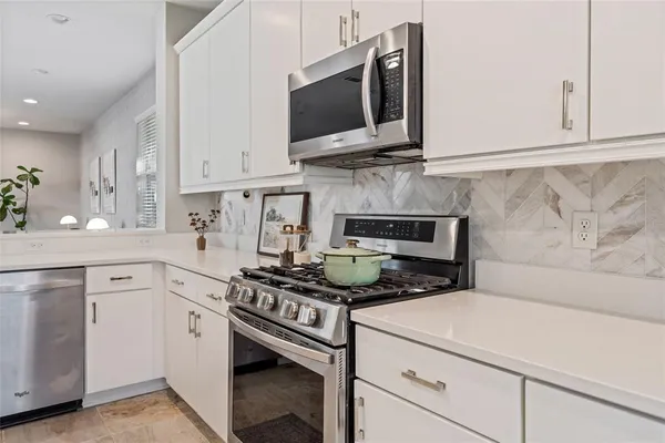 a kitchen with stainless steel appliances granite countertop a stove a sink and a microwave