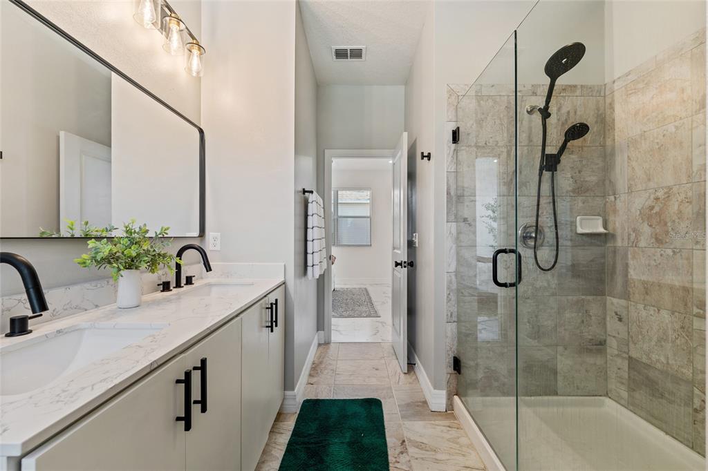 7935 Winter Wren Street Winter Garden, FL 34787 - Photo 21 of 36 a bathroom with a granite countertop sink a mirror a vanity and shower