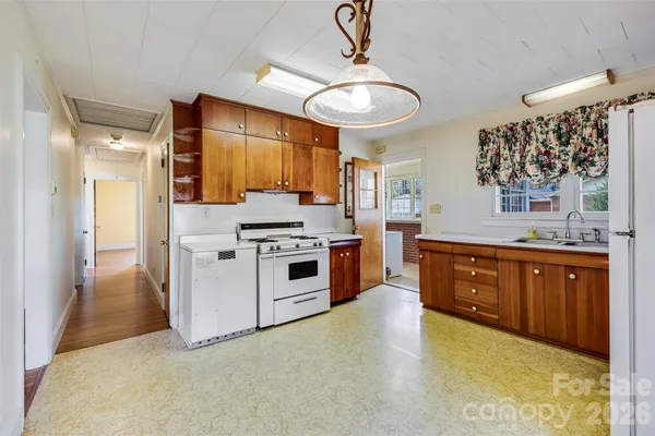 a large kitchen with stainless steel appliances granite countertop a stove a sink dishwasher and a refrigerator with wooden cabinets