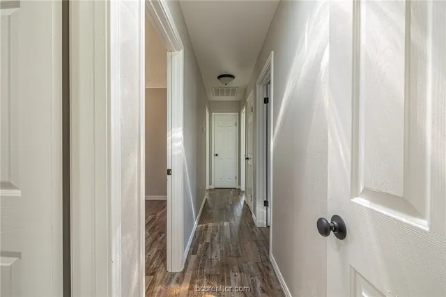a view of a hallway with wooden floor and closet area