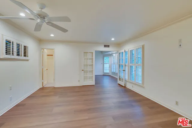 an empty room with wooden floor closet and windows