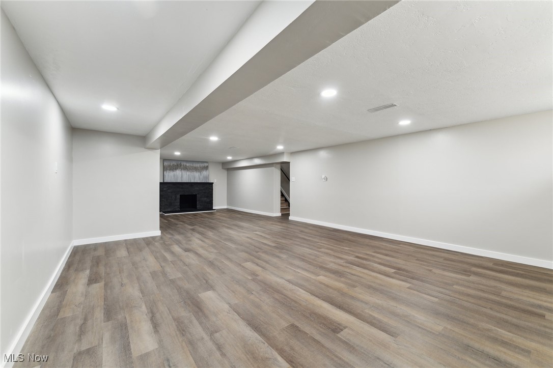 13225 Bagley Road Cleveland, OH 44130 - Photo 30 of 50 Unfurnished living room with baseboards, wood finished floors, recessed lighting, stairs, and a brick fireplace