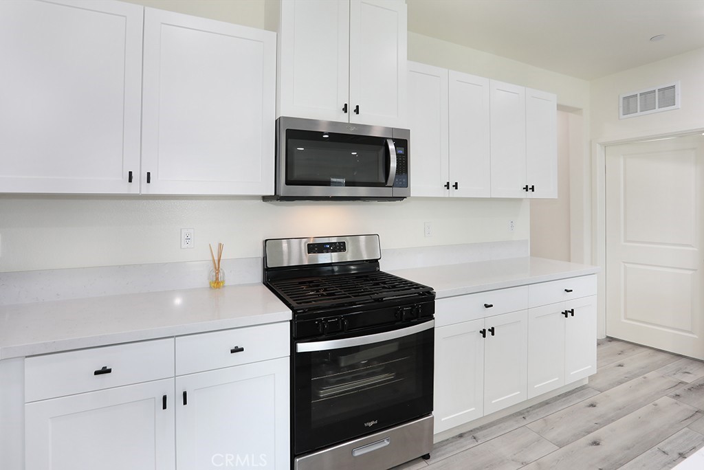 4067 Summer Corona, CA 92883 - Photo 12 of 28 a kitchen with white cabinets and black appliances