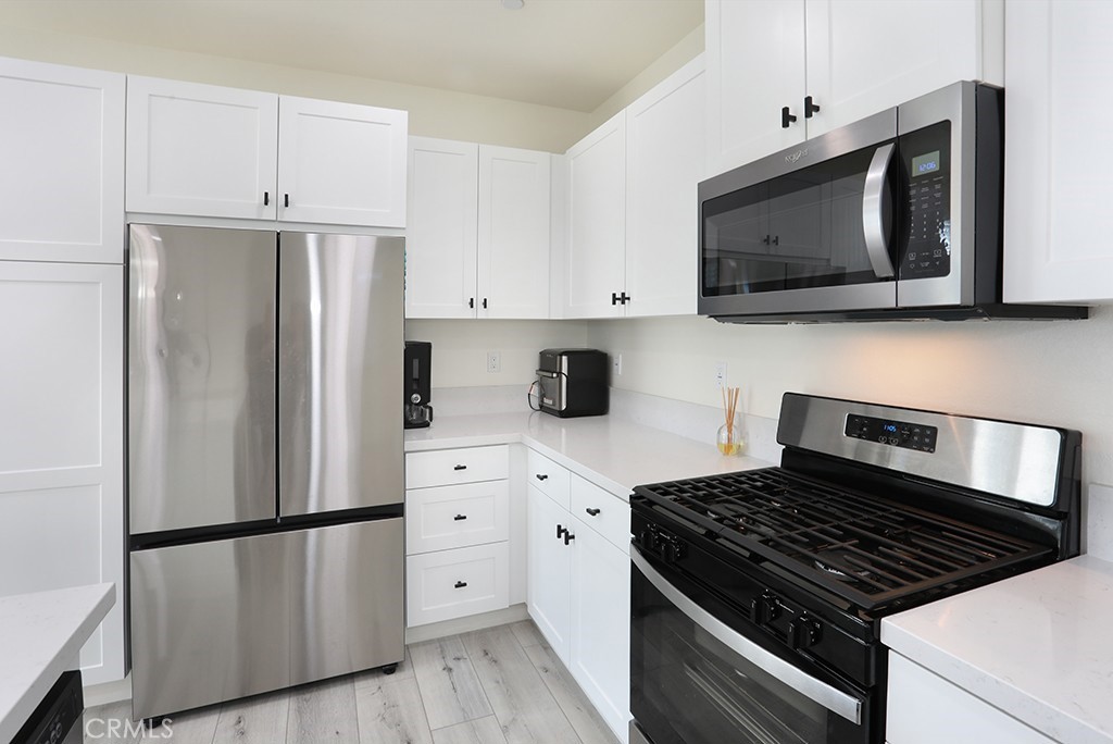 4067 Summer Corona, CA 92883 - Photo 13 of 28 a kitchen with stainless steel appliances white cabinets and a stove a refrigerator with wooden floor
