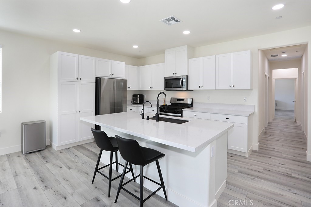 4067 Summer Corona, CA 92883 - Photo 10 of 28 a kitchen with kitchen island a refrigerator a stove a sink a dining table and chairs
