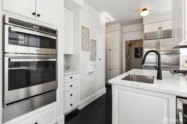 a kitchen with stainless steel appliances kitchen island a refrigerator sink and white cabinets