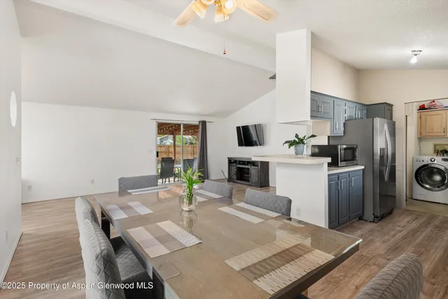 a open kitchen with stainless steel appliances kitchen island granite countertop a refrigerator a stove a sink a dining table and chairs with wooden floor