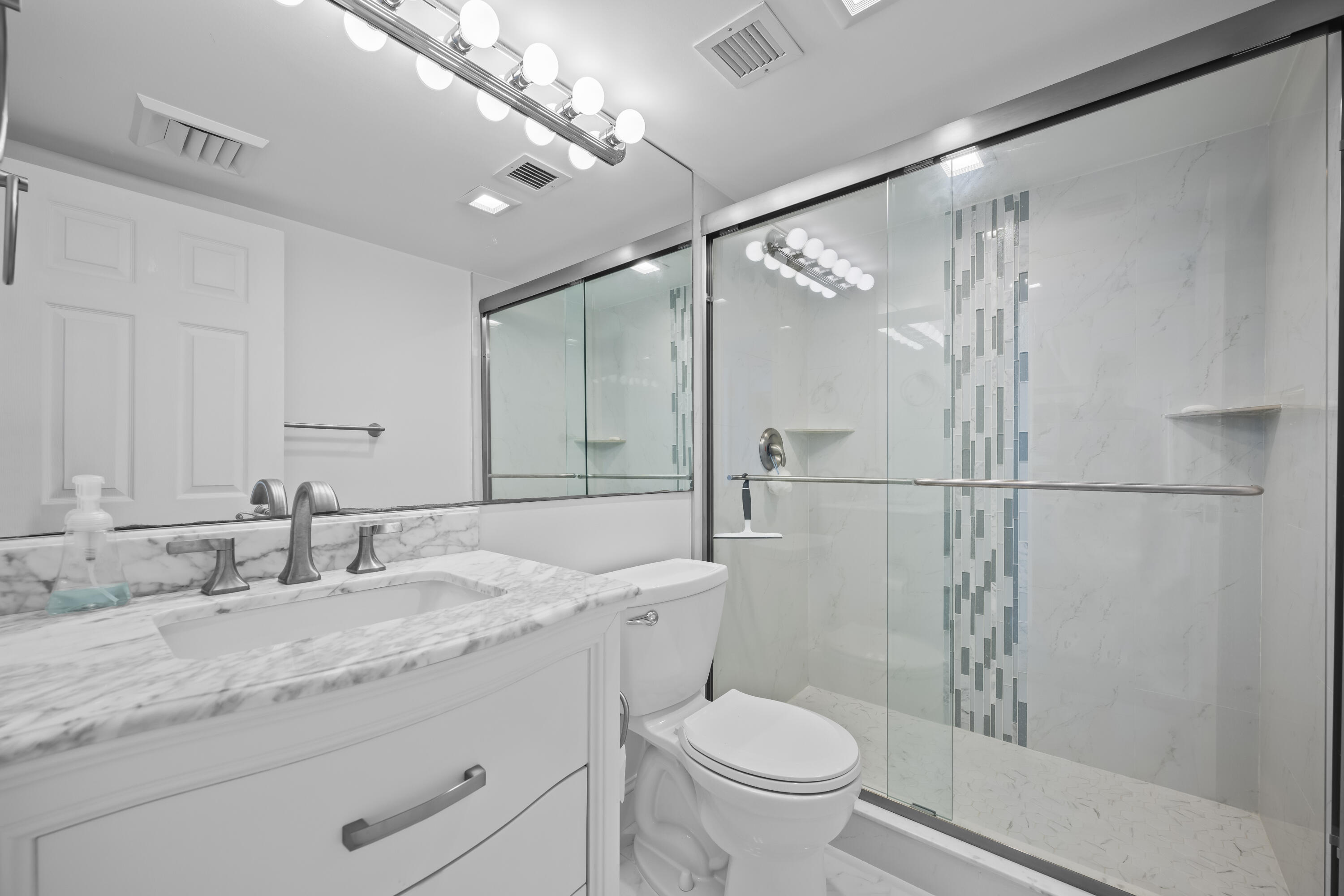 134 Lakeshore Drive, Unit 814 North Palm Beach, FL 33408 - Photo 17 of 30 a bathroom with a sink toilet a mirror and shower
