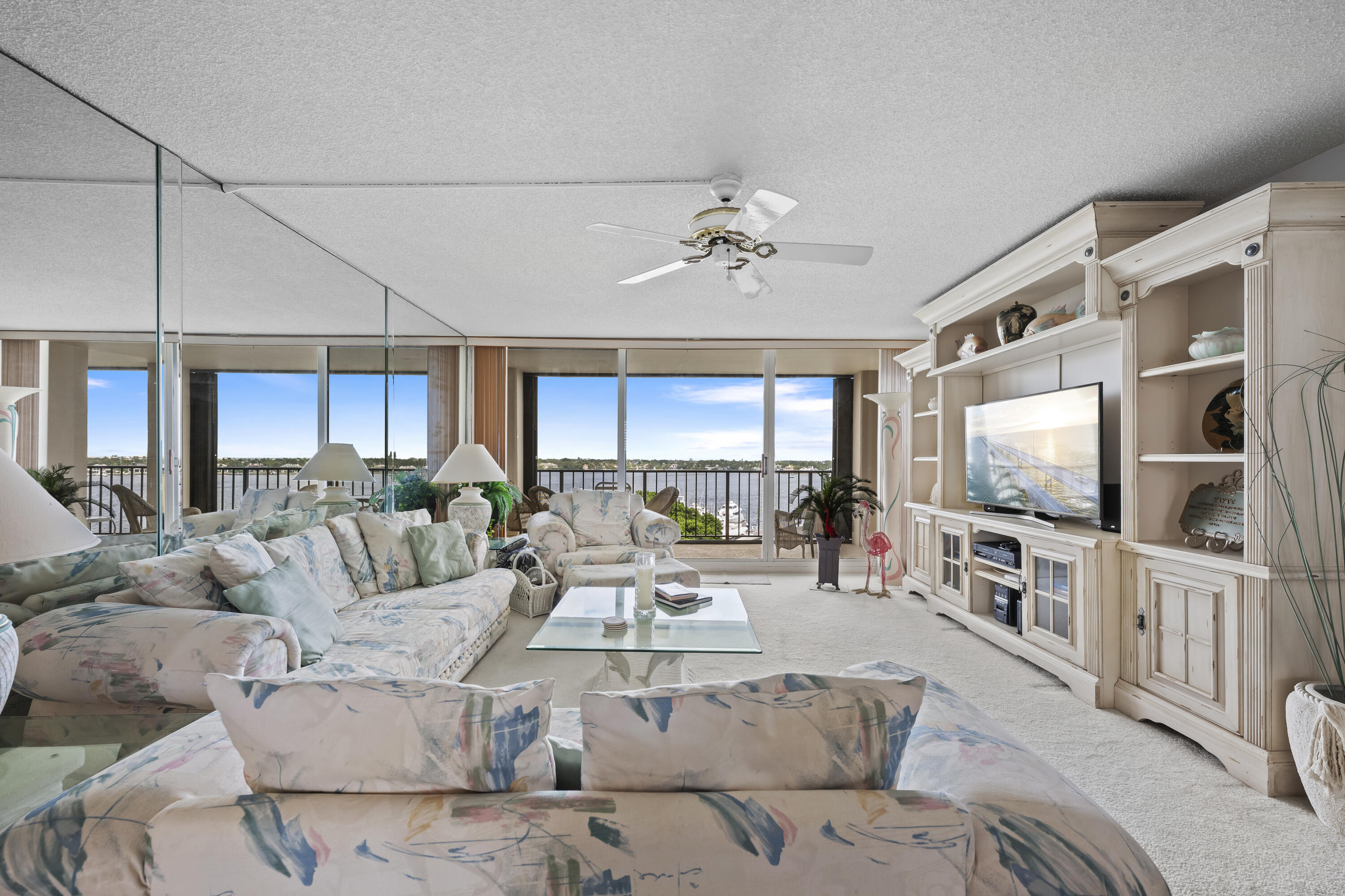 134 Lakeshore Drive, Unit 814 North Palm Beach, FL 33408 - Photo 7 of 30 a living room with furniture a flat screen tv and a chandelier