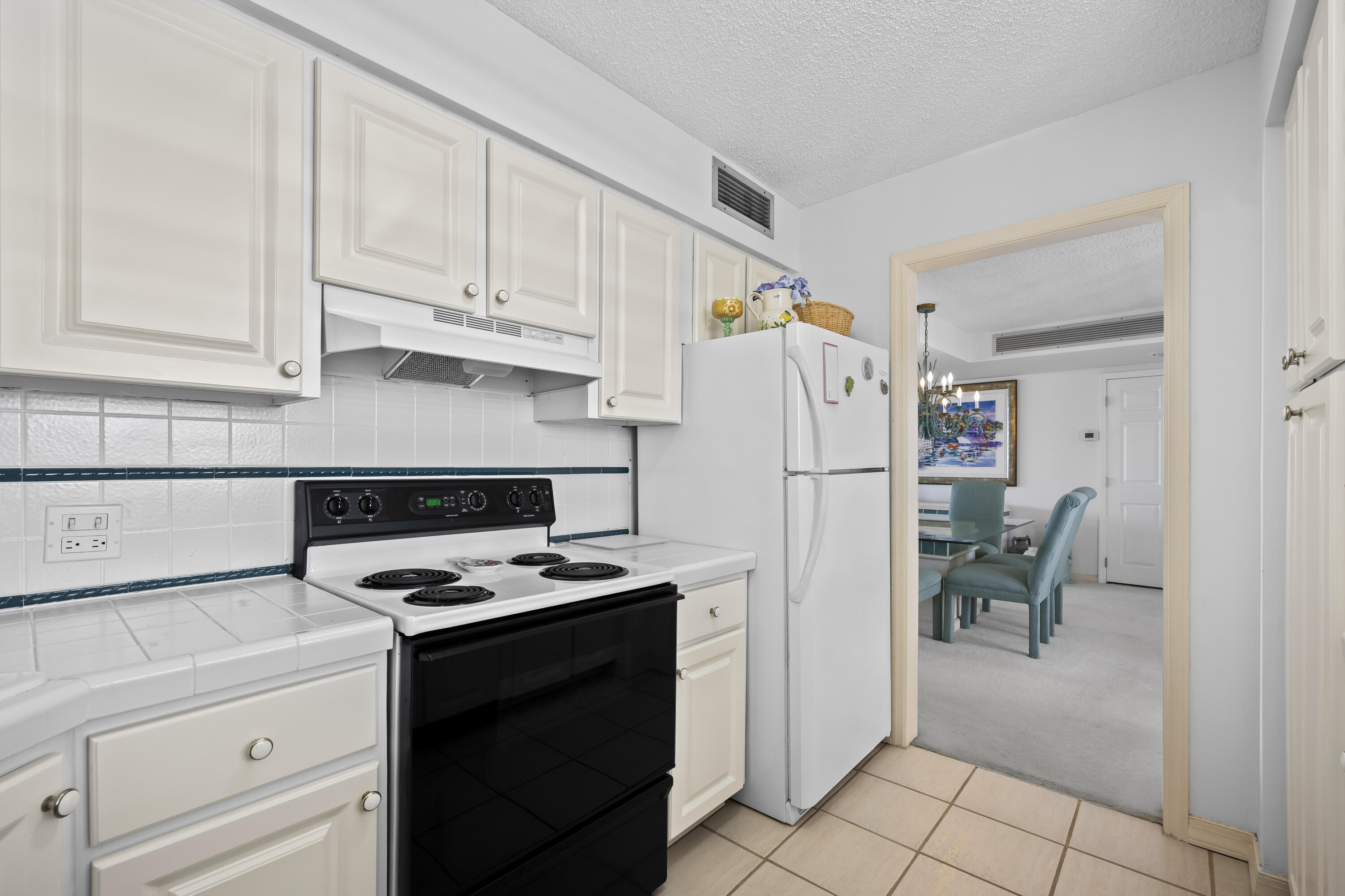 134 Lakeshore Drive, Unit 814 North Palm Beach, FL 33408 - Photo 9 of 30 a kitchen with a refrigerator a stove and white cabinets