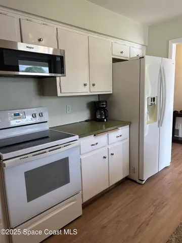 a kitchen with white cabinets and white appliances