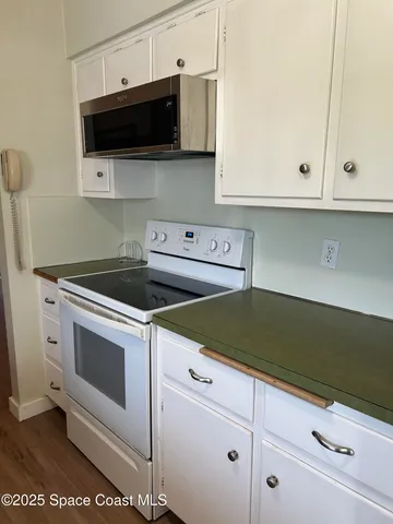 a kitchen with white cabinets and black appliances