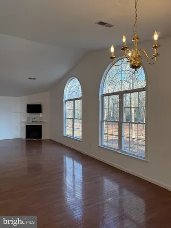 a view of an empty room with a fireplace and wooden floor