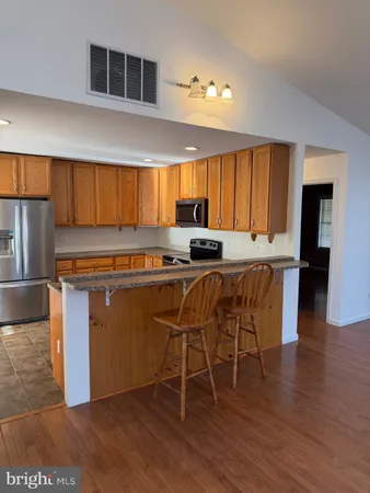 a kitchen with granite countertop a refrigerator and a stove top oven