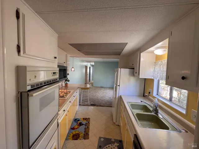 a kitchen with granite countertop a stove a sink and a refrigerator
