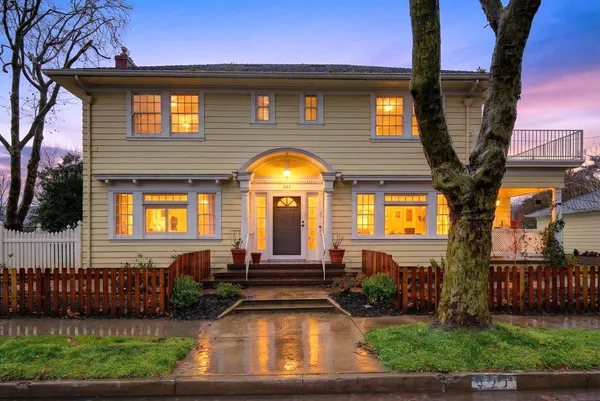 a view of a house with a small yard plants and large tree