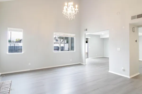 an empty room with wooden floor chandelier and windows