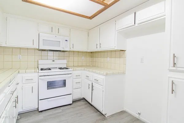 a kitchen with white cabinets and white appliances