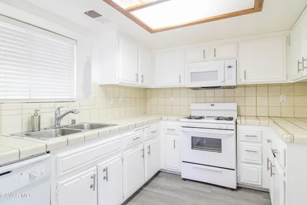 a kitchen with white cabinets sink and white appliances