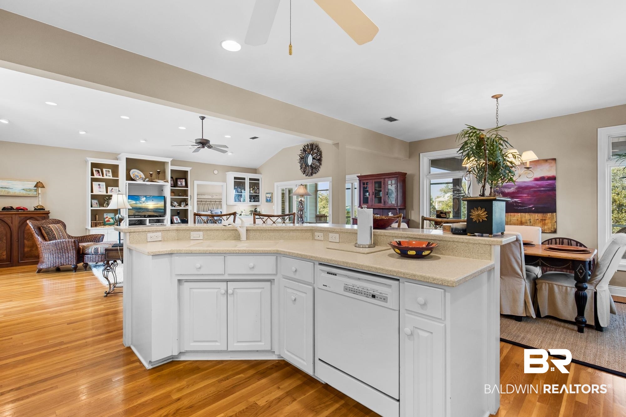 32191 River Road Orange Beach, AL 36561 - Photo 45 of 46 Kitchen featuring lofted ceiling, open floor plan, white dishwasher, a center island with sink, and white cabinetry