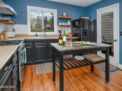 a kitchen with stainless steel appliances granite countertop a stove top oven a sink dishwasher and cabinets with wooden floor