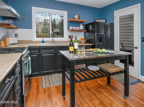 a kitchen with stainless steel appliances granite countertop a stove top oven a sink dishwasher and cabinets with wooden floor