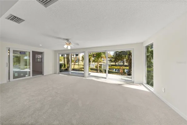 a view of an empty room with wooden floor and fan