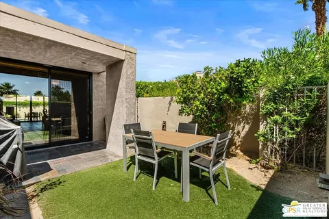 a patio with table and chairs and potted plants