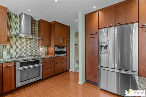 a kitchen with stainless steel appliances granite countertop a refrigerator stove and wooden floor