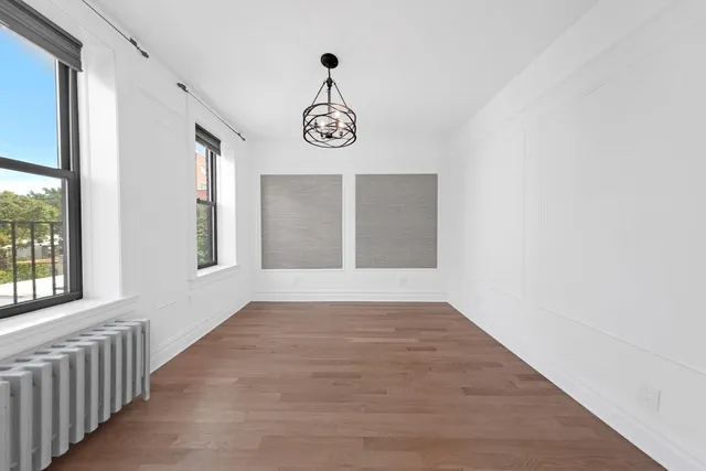a view of an empty room with wooden floor and window