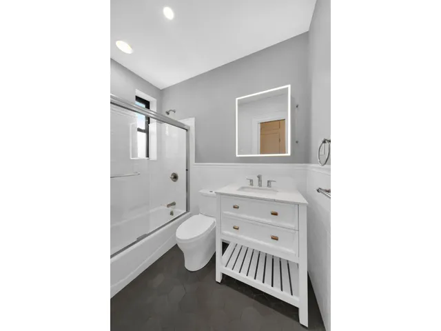 a bathroom with a toilet a sink a mirror and a shower